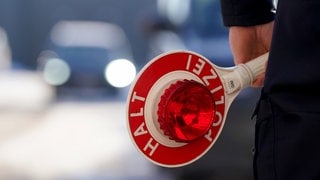 Ein Polizist hält eine Anhaltekelle in der Hand.
