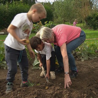 Rentnerpaar arbeitet mit Kindern im Garten.