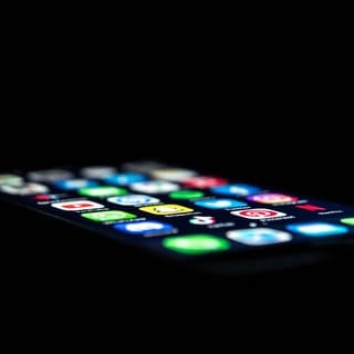Ein Smartphone leuchtet im Dunkeln. Mit Finanz-Apps haben Betrüger eine Frau aus Waldmohr (Kreis Kusel) um mehr als 87.000 Euro gebracht.