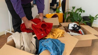 Eine Person räumt Kleidung und Gegenstände in Kartons.