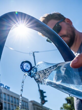 Ein Tourist aus Stuttgart füllt seine Wasserflasche am öffentlichen Wasserspender. Die Sommer werden immer heißer, doch aus Deutschlands Städten verschwinden die Bäume - knapp eine Million - und immer mehr Flächen sind versiegelt - ergibt der Hitze-Check der Deutschen Umwelthilfe.