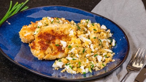 Schnitzel aus Blumenkohl: Nach Rezept ist das Gericht lecker zubereitet auf einem Teller mit einer Brösel-Garnitur aus Ei.