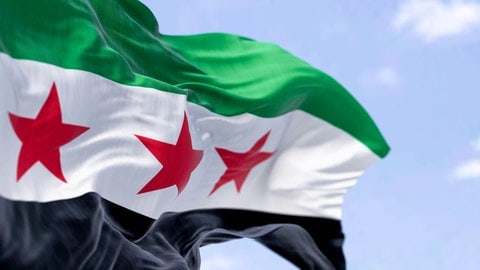 Eine Nahaufnahme der syrischen Flagge. Die rheinland-pfälzische Landesregierung hält nichts von einer Rückkehr syrischer Flüchtlinge in ihr Heimatland.
