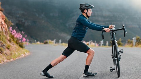 Mann dehnt sich bei einer Fahrrad-Tour