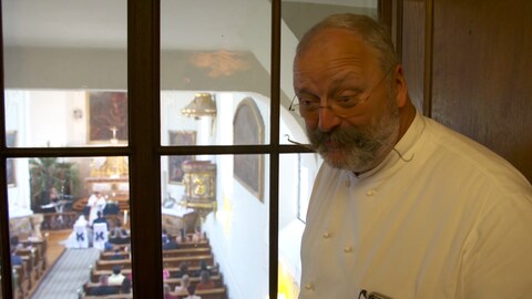 Mann steht auf Empore und beobachtet Trauung