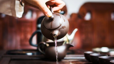 Eine Frau schenkt während einer chinesischen Teezeremonie den ersten Aufguss aus: Ein oft gehörter Ratschlag lautet: Schwarzen Tee solle man mit kochendem Wasser übergießen, bei grünem Tee dagegen soll das Wasser nicht heißer sein als 60 bis 80 Grad. Doch die Meinungen darüber gehen auseinander.