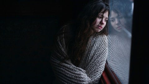 Eine Frau schaut traurig aus einem Fenster: Soldaten vergewaltigen Frauen und Mädchen, ein besonders schreckliches Kriegsphänomen. Sexualisierte Gewalt gilt als effiziente Waffe. Auch für den Krieg in der Ukraine sind solche Fälle belegt.