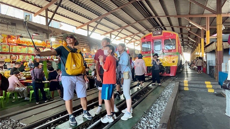 In Mae Klong posieren Menschen aus aller Welt vor dem Zug: Durch den „Schirm-klapp-weg“-Markt ist er berühmt geworden.
