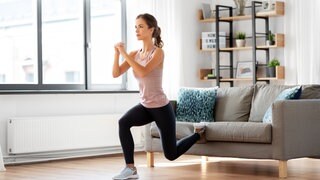 Frau macht Sportübungen im Wohnzimmer