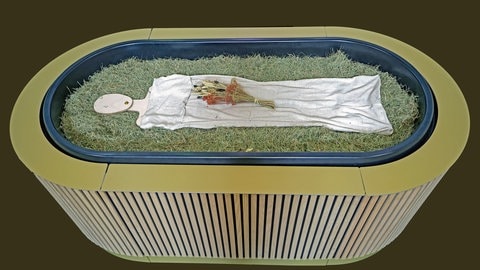 Heu, Stroh, Blumen und eine Holzfigur liegen in einem sogenannten „Kokon“ bei einem Pressegespräch zu der neuen Bestattungsform "Reerdigung" in der Kapelle auf dem Parkfriedhof Eichhof. Der Anbieter „Meine Erde“ bietet die neuen Bestattungsform an. Ein Leichnam wird auf Heu, Stroh und Grünschnitt gebettet, innerhalb von 40 Tagen wird er zu Erde.
