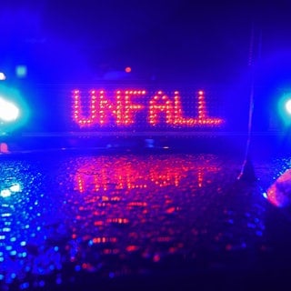 Polizeiauto mit blauen Sirenen. Auf dem Dach die leuchtende Anzeige: Unfall