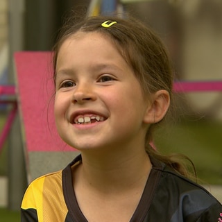 Letizia, 7 Jahre alt, grinst in die Kamera.