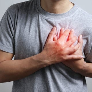 Mann greift sich mit beiden Händen ans Herz. Vorhofflimmern: Neue Behandlungsmöglichkeit mit weniger Nebenwirkungen macht Hoffnung.
