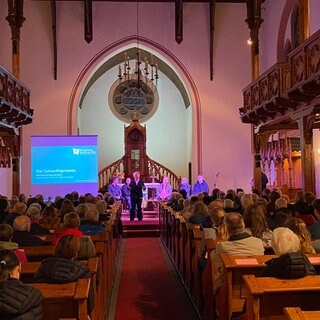 Eine Kirche mit versammelten Menschen - hier wird über den Sparkurs der evangelischen Kirche der Pfalz diskutiert.