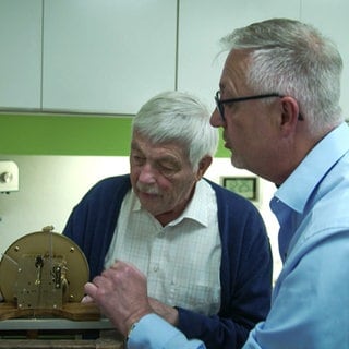 Zwei Männer arbeiten an einem Uhrwerk