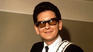 Sänger Roy Orbison in den 1960er Jahren mit einer Gitarre und schwarzem Anzug. Er starb 1988 im Alter von 52 Jahren.