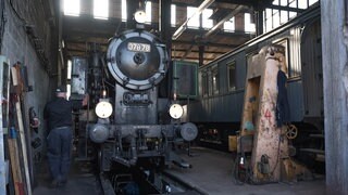 Eine alte Dampflok steht in einem Bahnlager