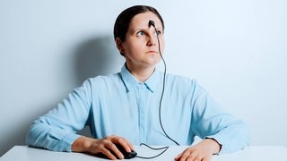 Frau mit PC-Maus und Kabel auf der Strin am Bürotisch