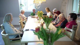 Ältere Menschen sitzen gemeinsam an einem Tisch.