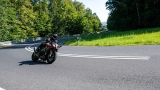Ein Motorradfahrer fährt in einer Kurve im Hambach zwischen Ebern und Untermerzbach (Unterfranken). Das sonnige Wetter lockt zu Ausflügen.