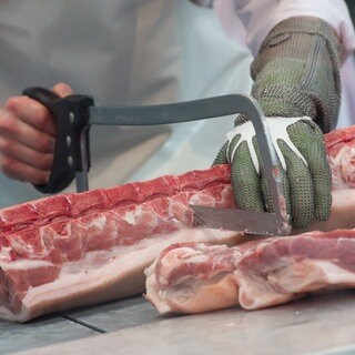 Eine Person zerlegt ein Stück Fleisch (Symbolbild): Das Unternehmen Boeser Frischfleisch kauft den Schlachthof Crailsheim