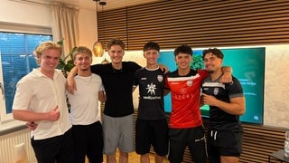 Fußballer MAxim Schmalz in der Mitte zwischen seinen Kumpels, alle Arm in Arm.
