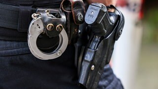 Polizist hat Handschellen und eine Dienstpistole am Gürtel befestigt