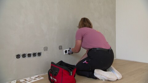 In diesem Wohnhaus bringt Sarah gerade Verkleidungen an einer Steckdosenleiste an.