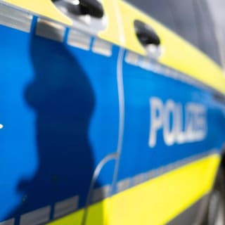 Seite eines Polizeiautos in Baden-Württemberg. Darauf ist der Schatten eines Polizisten zu erkennen. (Symbolbild)