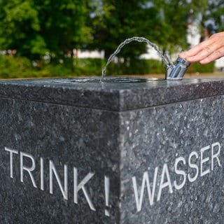 Ein Mann steht an einem Trinkbrunnen.