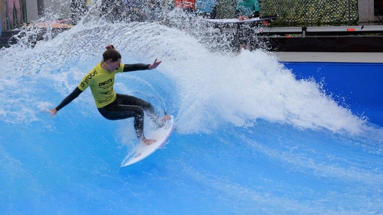 Eine Surferin macht eine Kurve auf einer künstlichen Welle.
