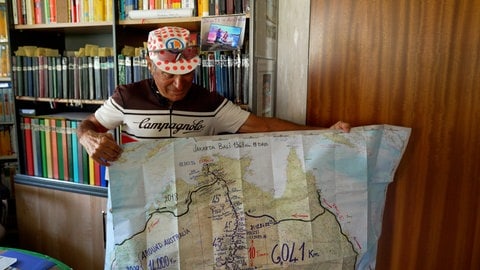 Ein Mann hält eine Landkarte hoch. Armando Basile zeigt seine Australien-Karte