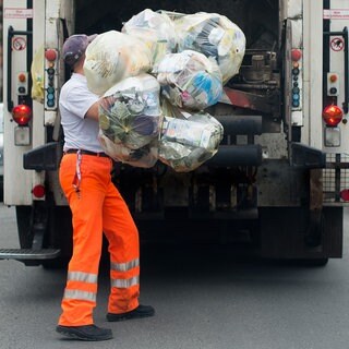 Symbolbild. Ein Mitarbeiter der Abfallbeseitigung wirft mehrere Gelbe Säcke in ein Müllfahrzeug.