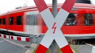 Ein Zug passiert einen Bahnübergang mit einem Andreaskreuz 