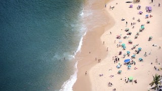 Menschen an einem Strand | Das sind die Reisetrends für euren Urlaub in 2026