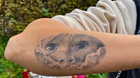 Eine Tatöwierung auf einem Unterarm: sie zeigt das Gesicht eines kleinen Kindes, das mit großen, dunklen Augen durch ein Loch in den Wolken schaut. In unserer Reihe "SWR1 Neuanfang" portraitieren wir Luana: Sie hat einen Raserunfall überlebt, ihr Mann und ihr Baby starben. Trotz des großen Traumas kämpfte sie sich zurück ins Leben.