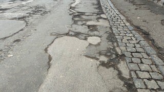 Auf einer Straße in Bad Kreuznach befinden sich viele Schlaglöcher und Straßenschäden.