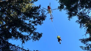 Rettungskräfte von DRF Luftrettung und Bergwacht werden in den Rettungshubschrauber gezogen.
