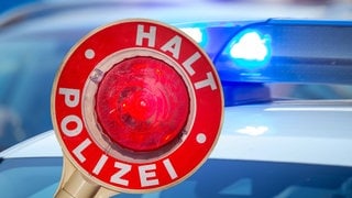 Eine Polizeikelle vor einem Streifenwagen