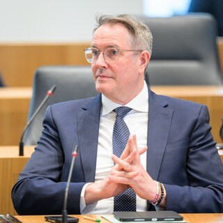 Alexander Schweitzer (SPD) sitzt mit fröhlichem Gesichtsausdruck und verschränkten Fingern im Landtag von Rheinland-Pfalz. Er ist ehemaliger Ministerpräsident von Rheinland-Pfalz und wird jetzt Bundesarbeitsminister.