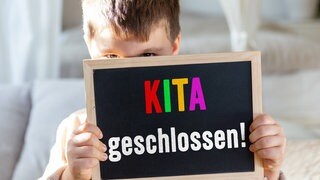 junge hält Tafel hoch, auf der steht: Kita geschlossen. Ver.di hat zu Streiks im öffentlichen Dienst aufgerufen, auch in Karlsruhe.