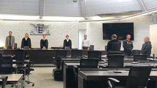 Mehrere Menschen stehen im Saal des Landgerichts Stuttgart. Anfang Mai hat der Prozess gegen einen 47-jährigen Mann begonnen. Er soll seine Lebenspartnerin im Juli 2024 getötet und eingemauert haben.