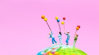 Miniaturfiguren stehen auf einem Globus: Wie groß müsste die Erdkugel sein, damit alle Menschen dort einen Stehplatz hätten?
