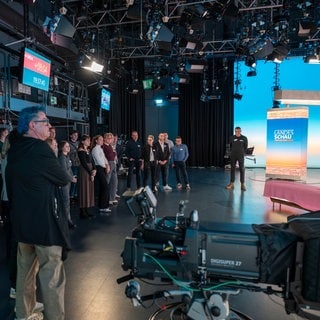 Das Bild zeigt eine Gruppe von Menschen, die an der Besucherführung im SWR teilgenommen haben. Sie stehen in einem Studio.