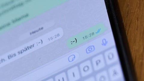 Ein Smiley ist in einem Chat auf einem Handydisplay zu sehen. (Symbolbild) 