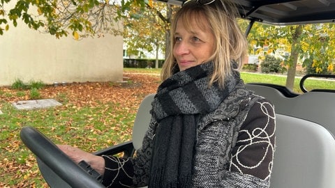 Simone Maria Dietz sitzt am Steuer des Golfmobils. Der Wagen ist auf dem Hauptfriedhof Karlsruhe für den Transport von Besuchern an Allerheilgen im Einsatz.