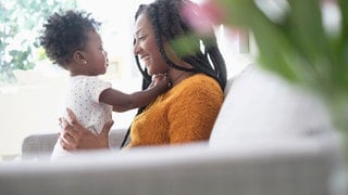 Eine Mutter hält ihr Kind und spielt und spricht mit dem kleinen Mädchen: Die Wörter für die eigeneMutter haben in allen bekannten Sprachen einen "m"-Laut. Die Forschung kennt viele solcher sprachlichen Universalien. 