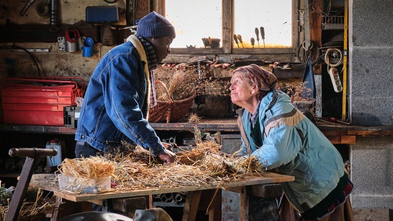 Tayo und Lioba bauen in der Traktorscheune gemeinsam an einer Strohpuppe