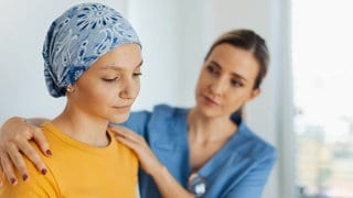Junge Krebspatientin; Ärztin legt ihr aufmunternd die Hände auf die Schultern: Wer Krebs überlebt hat, leidet häufig jahrelang unter körperlichen und psychischen Folgen. Individuelle medizinische Angebote können die "Survivor" unterstützen. 