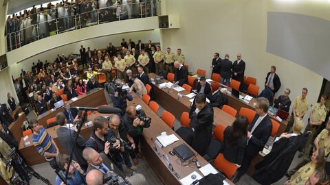 Die Angeklagte Beate Zschäpe (Gruppe rechts unten in der Mitte) steht vor Beginn des Prozesses am 6. Mai 2013 im Gerichtssaal in München neben ihren Anwälten Wolfgang Stahl (links), Wolfgang Heer und Anja Sturm (rechts) und dreht den Zuschauern den Rücken zu.